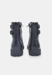 Stivaletti neri in pelle con due fibbie regolabili e cerniere sul retro. Suola spessa, punta arrotondata e texture liscia.
