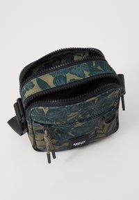 Borsa a tracolla con motivo camouflage, cerniere nere, due scomparti, anello in tessuto e etichetta del marchio sulla parte anteriore.