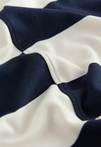 Close-up van marineblauw en wit gestreept stof met zichtbare stiksels en een zachte textuur.