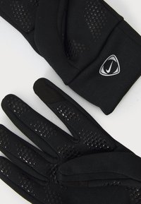 Mânuși sport negre, cu un grip texturat, având secțiuni perforate pentru respirabilitate și un logo pe manșetă. Material moale și flexibil.