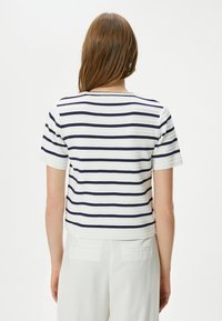 Stribet kortærmet top i hvid og navy, med rund halsudskæring og cropped design. Strikket tekstur med horisontalt linjemønster.