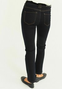 Tummansiniset farkut slim fit -leikkauksella, joissa on korkea vyötärö, takataskut ja erottuva oranssi tikkaus. Sileä rakenne, jossa on hieman joustoa.