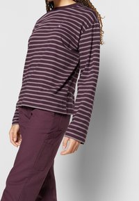 Long-sleeve striped shirt in dark purple with light gray stripes, featuring a crew neck and relaxed fit, paired with dark purple pants.