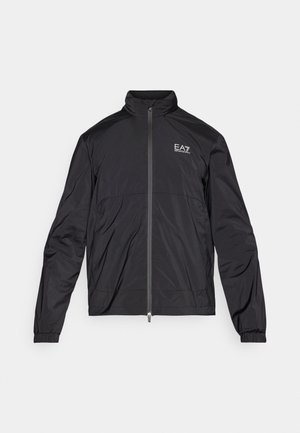 Fekete, könnyű dzseki magas gallérral, teljes elülső cipzárral, rugalmas mandzsettákkal és EA7 logóval a bal mellrészen. Sima, matt felület.