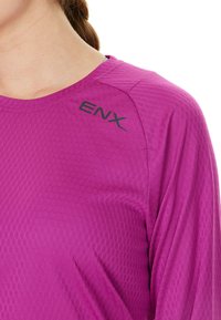 Lila långärmad träningsskjorta med en texturerad, bikupemönster. Har en rund halsringning och "ENX"-logotyp tryckt i svart på axeln.