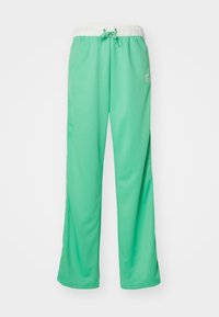 Nike sweatpants in light green, featuring a white drawstring waistband, wide legs, and logo detail in contrasting color on the side.