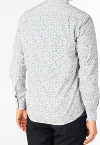 Koszula z długim rękawem w białym materiale z niebieskim wzorem kwiatowym. Posiada zaokrąglony dół i mankiety na guziki. Teksturowana powierzchnia.