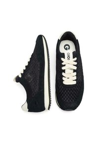 Zapatillas negras con textil de malla, acentos de ante, cordones crema y una suela blanca. Presenta un logo en la lengüeta y paneles laterales texturizados.