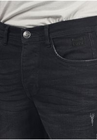 Svarta denimjeans med klassisk passform, som har en framficka, slitna detaljer och en liten märkesläderlapp på midjebandet.