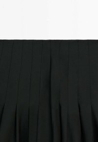 Tissu noir plissé avec des détails de couture verticale, présentant une texture lisse et structurée.