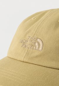 Μπεζ σκουφάκι του μπέιζμπολ με κεντημένο λογότυπο "THE NORTH FACE" στο μπροστινό πάνελ πάνω σε απλό ανοιχτόχρωμο φόντο.