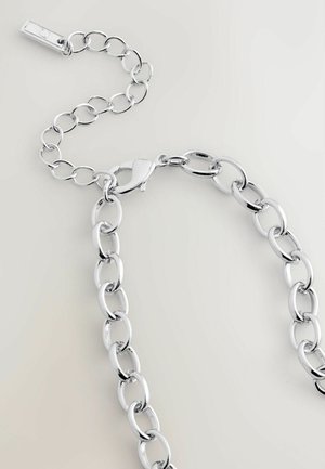 Collier en chaîne argentée avec des maillons ovales, un fermoir à homard et une chaîne extensible ajustable sur un fond clair.
