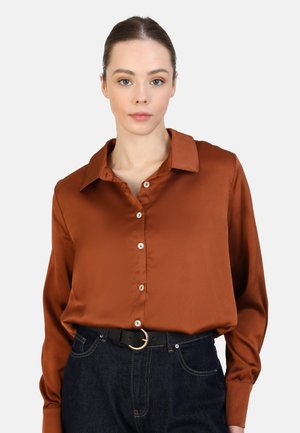 Brown satin blouse with a collar and button-down front, featuring a smooth texture. Worn with high-waisted dark denim and a black belt.