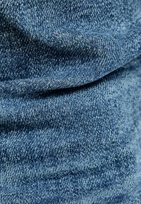 Tejido de mezclilla en azul medio con texturas variadas, con un patrón de tejido clásico y un sutil pespunte en contraste.