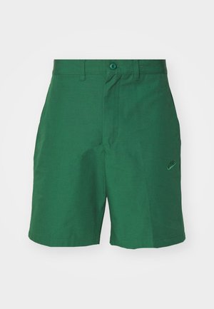 Green, woven shorts with a flat front, two side pockets, and a subtle Nike logo embroidered on the left leg. Features a button closure.