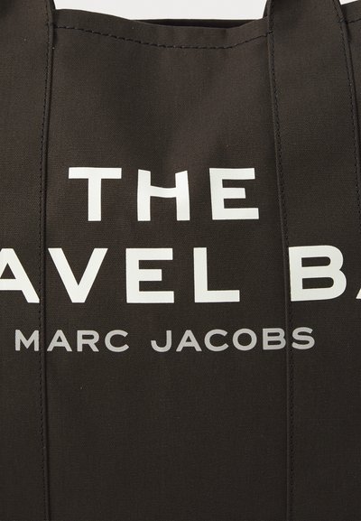 Borsa a spalla nera in tela con testo bianco. "LA BORSA DA VIAGGIO" e "MARC JACOBS" stampati in modo prominente. Presenta doppi manici e un design strutturato.