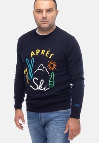 Granatowy sweter z kolorową haftowaną grafiką przedstawiającą sprzęt narciarski, góry, słońce i butelkę. Rękawy i dół ściągacze, wykonany z miękkiego materiału.