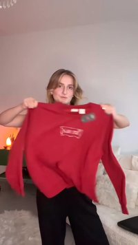 Sweatshirt rosso con maniche lunghe e collo rotondo, caratterizzato da un logo metallico sul davanti. Realizzato in un tessuto morbido e texture.