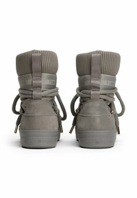 Sneaker grigio alla caviglia con colletto imbottito e a coste, chiusura con lacci, materiale in suede e suola in gomma. Presenta il logo sul retro e dettagli decorativi.