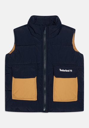 Doudoune sans manches navy avec col montant, deux poches beiges, fermeture éclair à l'avant et logo Timberland sur la poche gauche. Texture lisse, design isolé.