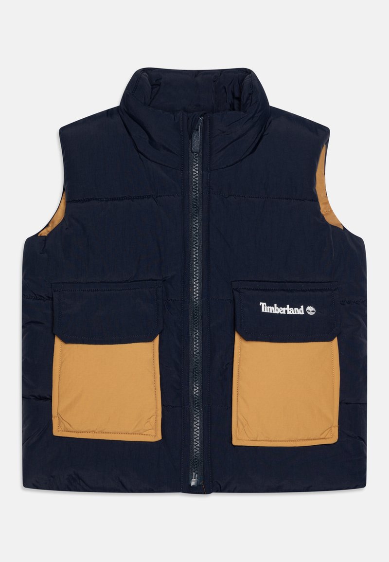 Gilet trapuntato blu navy con colletto alto, due tasche color beige, chiusura frontale con zip e logo Timberland sulla tasca sinistra. Tessuto morbido, design isolato.