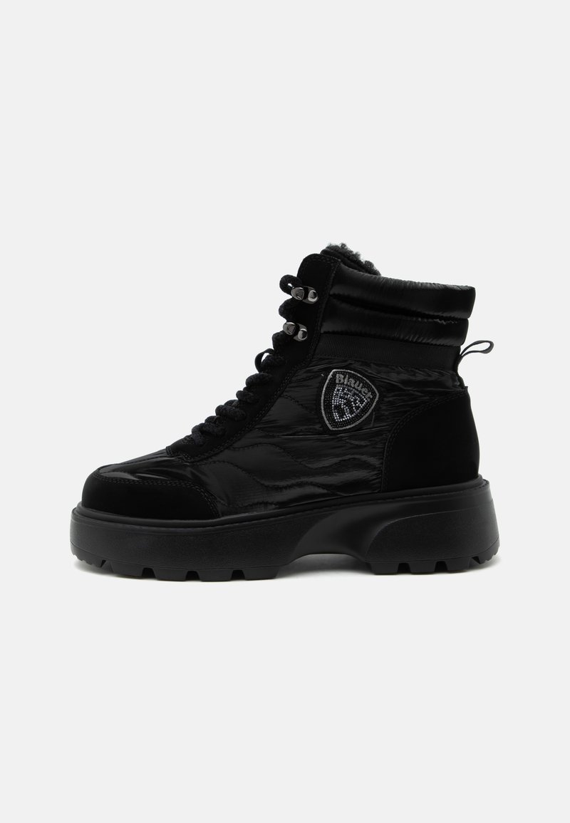 Botte d'hiver noire montante avec semelle épaisse, fermeture à lacets à l'avant, col rembourré et écusson logo en forme de bouclier sur le côté.