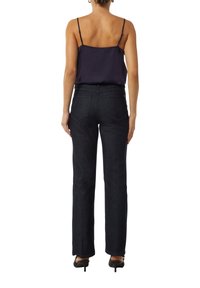 Granatowe dżinsy z prostymi nogawkami, o średnim stanie, z tylnymi kieszeniami i subtelnymi detalami szycia. Połączone z ciemnym topem na ramiączkach.