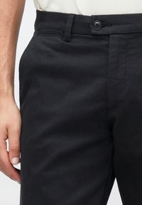 Mørkegrå bukser i tekstureret stof, med knaplukning, sidelommer og skræddersyet pasform.
