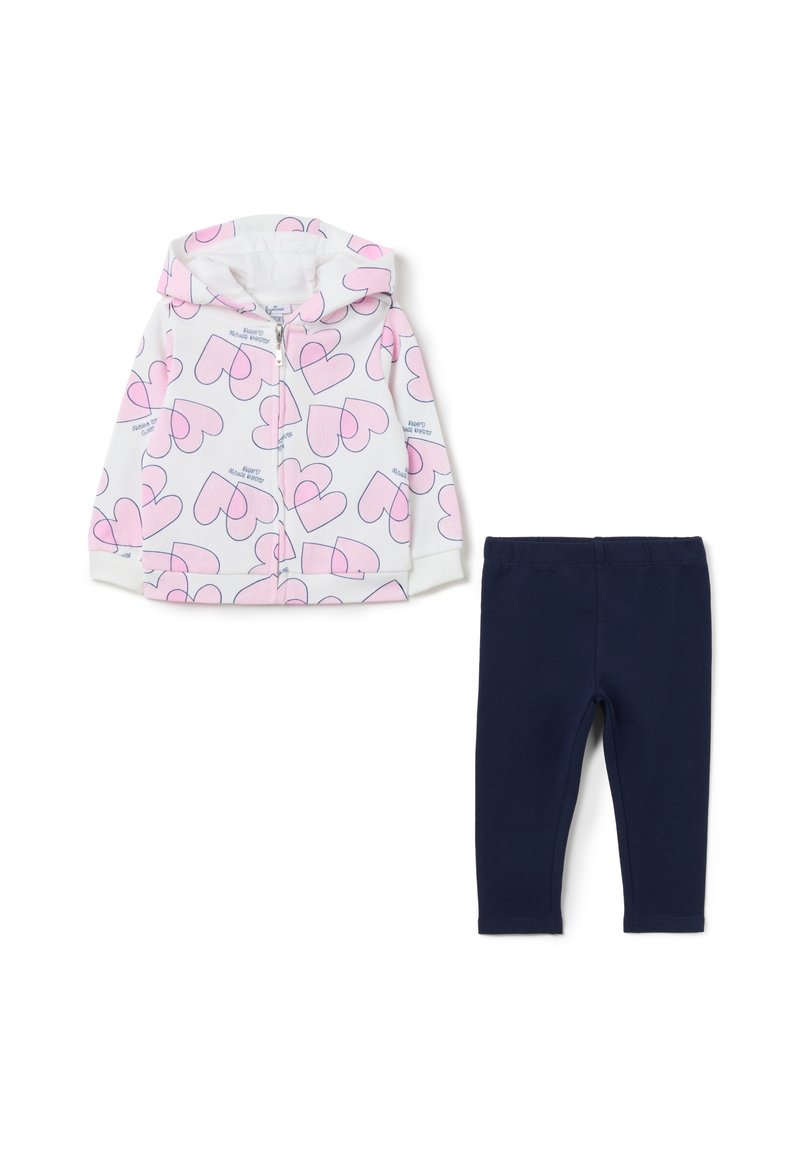 Chaqueta con capucha en blanco con estampado de corazones rosa, combinada con leggings azul marino. La chaqueta tiene cierre de cremallera y puños acanalados.