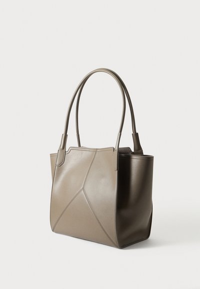 Sac fourre-tout en cuir taupe avec des motifs géométriques cousus et deux longues poignées arrondies sur fond blanc.