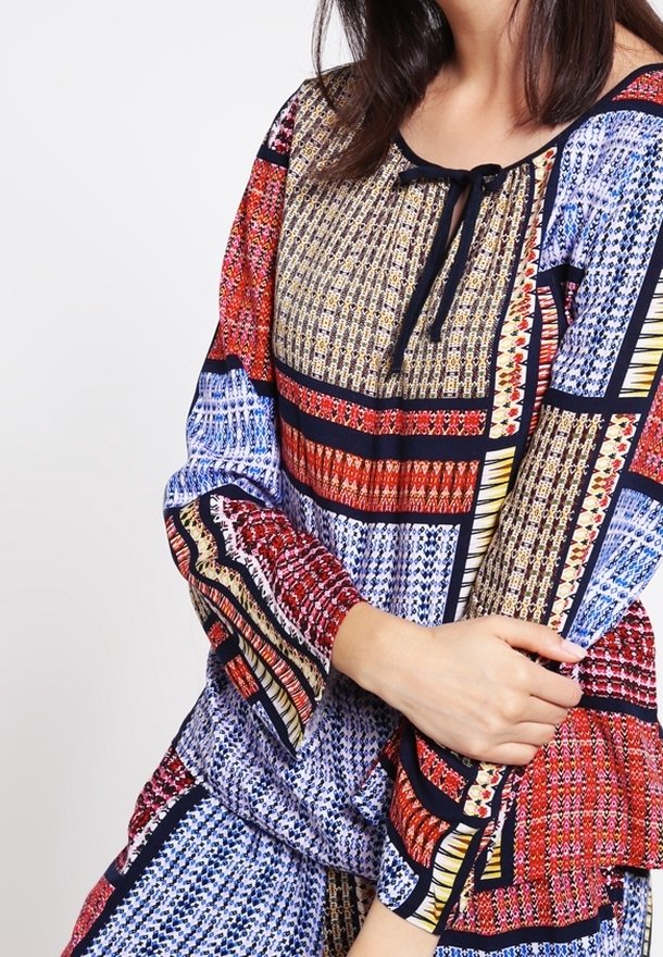 Blusa a fantasia multicolore con scollo regolabile, maniche a campana e intricati motivi geometrici nei toni del blu, rosso e oro.