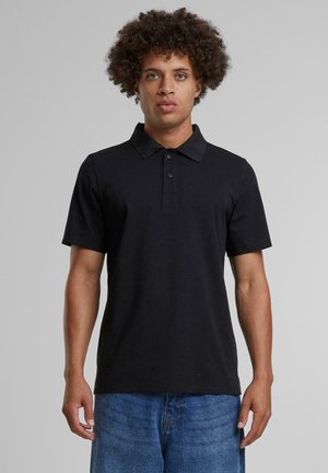 Camisa polo negra de manga corta, con cuello, tapeta de tres botones y dobladillo recto, hecha de una suave mezcla de algodón.