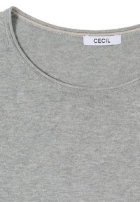 Col en tricot gris clair d'un t-shirt avec une petite étiquette de marque blanche portant l'inscription "CECIL" cousue à l'intérieur du col.