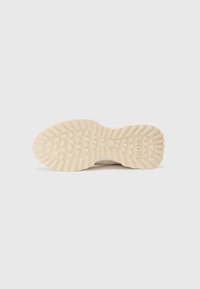 Semelle de sneaker, présentant un design en caoutchouc épais, des rainures texturées pour l'adhérence, et une marque "BOSS" en relief de couleur claire.