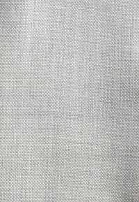 Tissu gris clair avec un tissage texturé, des fibres réparties de manière uniforme, une apparence légèrement rugueuse et sans motifs ou accents distincts.