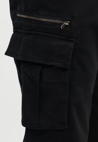 Μαύροι cargo παντελόνες με πλαϊνή τσέπη με φερμουάρ, απαλό ύφασμα και χαλαρή, ίσια γραμμή.