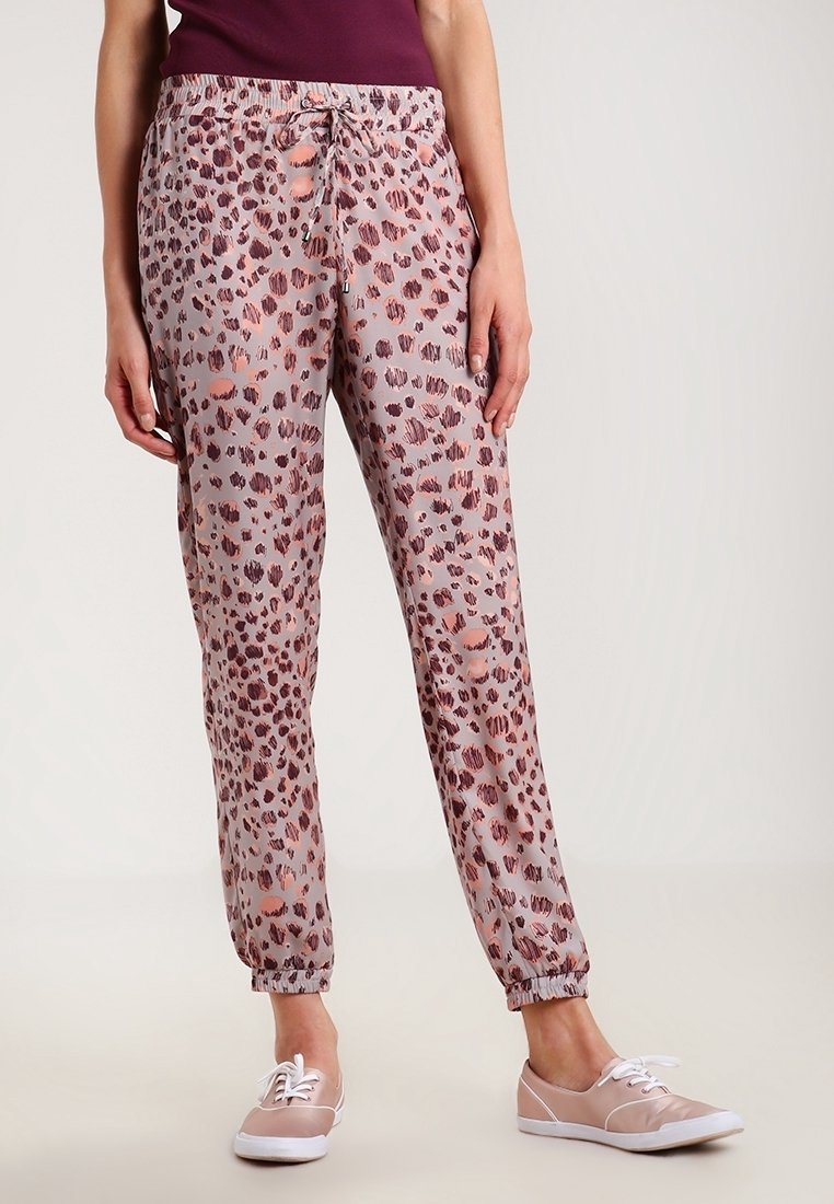 Różowe spodnie w panterkę z elastycznym pasem i sznurkiem do wiązania. Posiadają zwężane nogawki z elastycznymi mankietami. Wykonane z lekkiego materiału.
