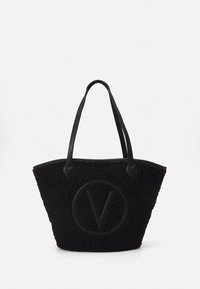 Svart toteväska gjord av strukturerat material med en stor rund logotyp som har ett "V". Den har robusta svarta handtag och en rymlig, öppen design.