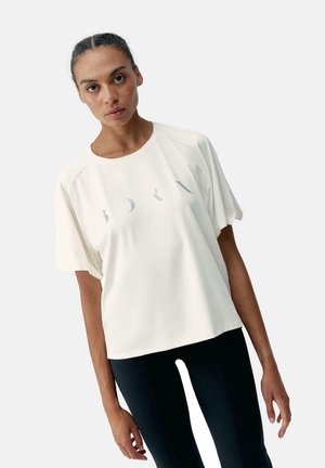 Tricou de culoare crem deschis, cu mâneci scurte și croială relaxată, având un model imprimat subtil pe piept. Material neted și decolteu rotund.