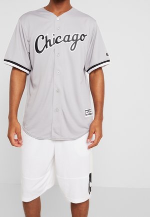 Maglietta da baseball grigia con "Chicago" in scritta nera, sei bottoni e maniche a righe nere, abbinata a pantaloni bianchi con logo.
