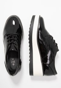 Chaussures à lacets en cuir verni noir avec une finition brillante, semelle intermédiaire blanche épaisse et semelle extérieure en caoutchouc noir texturé. Design classique avec bout arrondi.