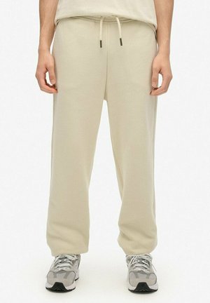 Lys beige sweatpants i en afslappet pasform, med elastisk talje og snor, samt to sidelommer. Båret med grå sneakers.