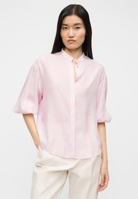 Ανοιχτό ροζ κοντομάνικο πουκάμισο με μαντίλα σε στύλ μανταρινιού, κουμπιά μπροστά και υφή με κάθετες ρίγες. Μαλακό ύφασμα με άνετη εφαρμογή.