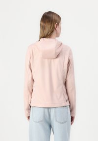 Απαλή ροζ, ελαφριά ζακέτα με κουκούλα, που διαθέτει ομαλή υφή και εφαρμοστή γραμμή. Το πίσω μέρος περιλαμβάνει ραφές στους ώμους και λεπτομέρεια λογότυπου.