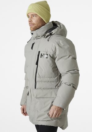 Parka isolata grigia chiara con cappuccio, accenti neri tra cui la cerniera e il logo, e tessuto testurizzato. Include tasche per le mani e coulisse regolabili.