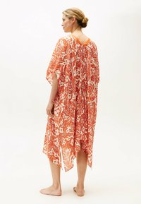 Kaftano floreale arancione e bianco con maniche corte, caratterizzato da un design ampio e fluido e da una scollatura a V sul retro; realizzato in tessuto leggero e trasparente.