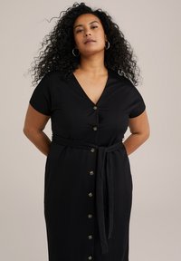 Vestito nero con bottoni, maniche corte, scollatura a V e vita legata. Presenta una superficie liscia e dettagli decorativi con bottoni sulla parte anteriore.