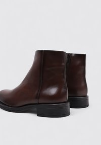Brown leather ankle boots with a smooth texture, side zipper closure, and a low black heel. Classic, streamlined silhouette.