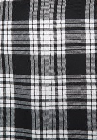 Randig tyg i svart och vitt med ett rutig mönster där linjerna har varierande bredder. Slen yta med en lätt lyster.