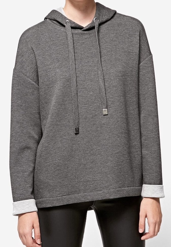 Osoba ubrana w luźny szary hoodie związywany sznurkiem i białymi mankietami, w połączeniu z czarnymi skórzanymi spodniami.